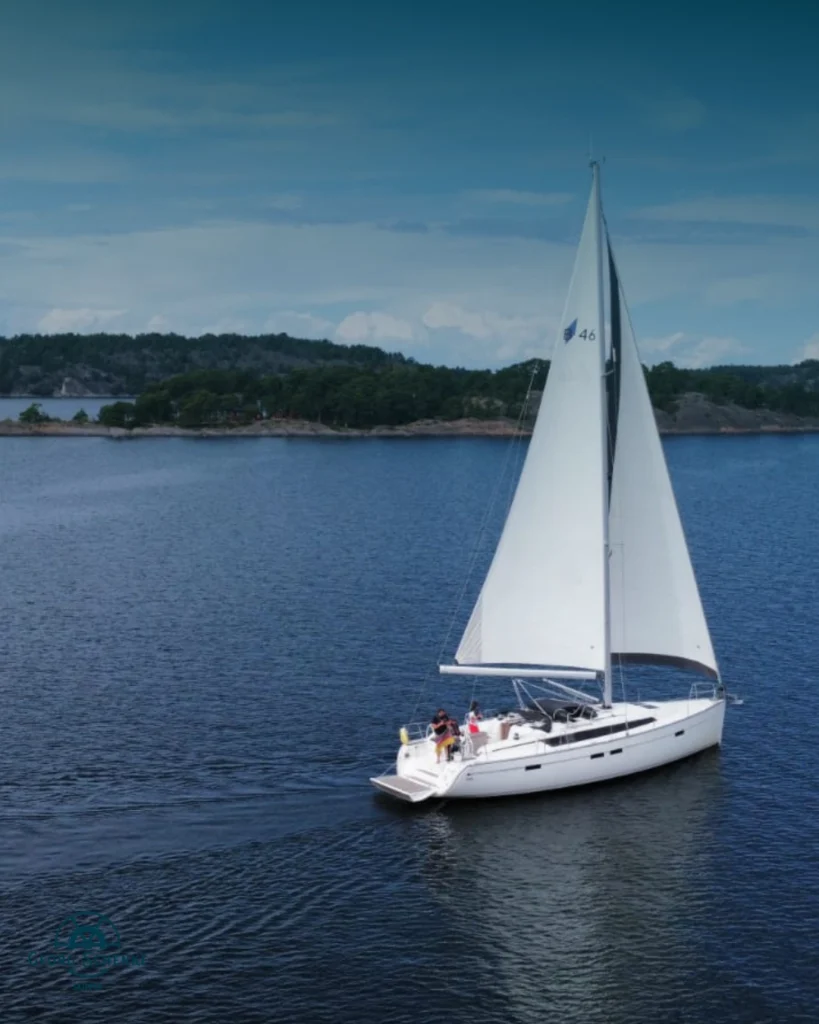 Eine weisse Segelyacht segelt in leichtem Wind und vollen Segeln in der Flensburger Förde