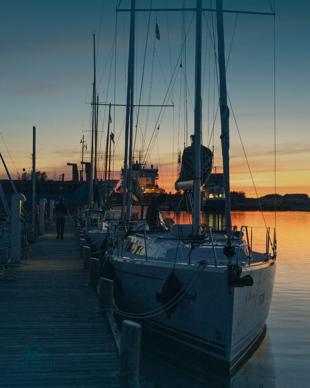 Eine Segelyacht liegt im Hafen bei Sonnenuntergang, wir sehen den Bug